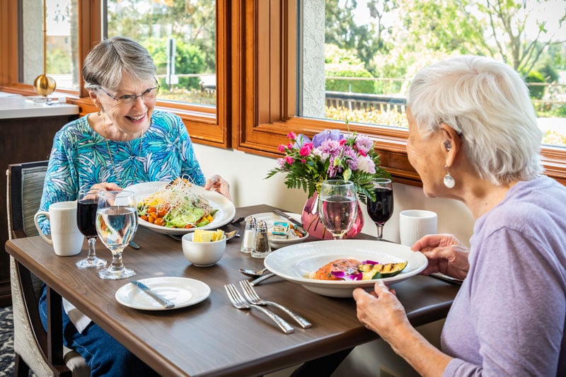 two senior women sitting at a cafe eating a healthy meal